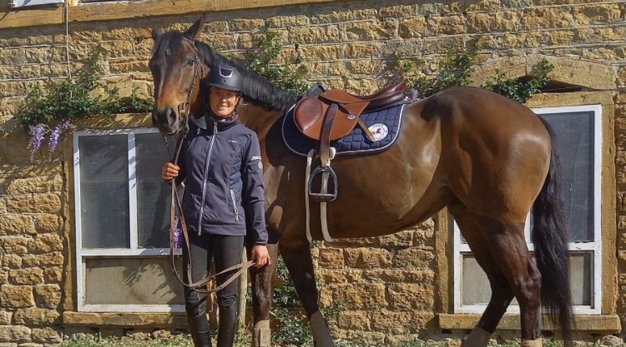 Cavalière tenant son cheval sellé devant les écuries du Centre Équestre de Denicé