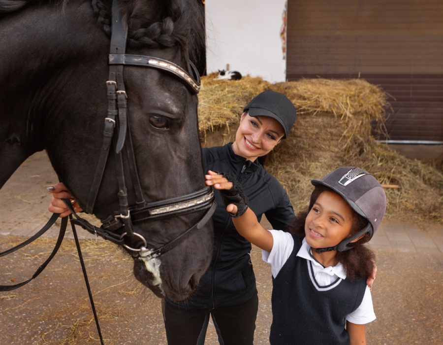 Élève d’équitation caressant un cheval sous la supervision de sa monitrice