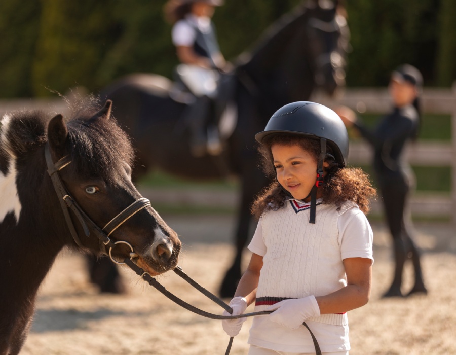 Jeune cavalière tenant un poney pendant un cours d’équitation